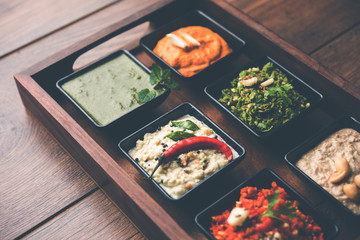 Group of Indian Chutneys includes coconut, Peanut, green and red chilly, garlic and pudina served in small square shape bowls. selective focus
