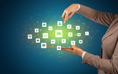 Female hand touching tablet with application icons above