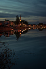 View of a town with church near Gouda, Holland at blue hour. Beautiful reflections of a moody sky.