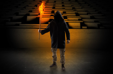 Ugly, aberrant man coming out from the labyrinth with burning flambeau on his hand
