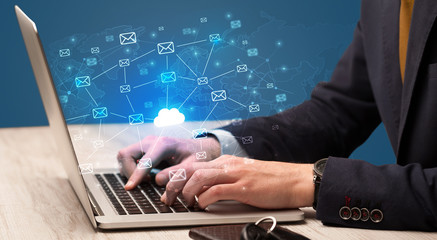 Fototapeta premium Businessman hand sending a bunch of messages on laptop with cloud computing concept 