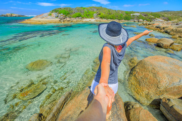 Australia summer holidays. Follow me POV. Woman in hat holding hand of her friend at William Bay National Park, Denmark region, Western Australia. Tropical destination of Madfish Beach.