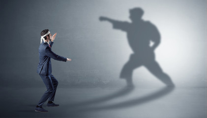 Fototapeta na wymiar Businessman fighting with his strong karate man shadow 