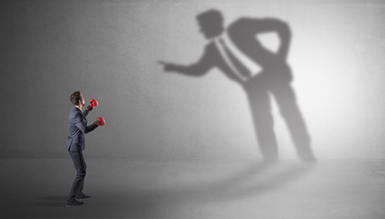 Businessman fighting with his bossy yelling shadow
