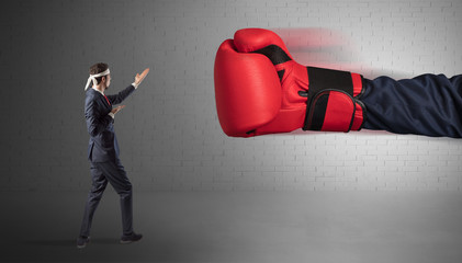 Tiny businessman fighting with boxing gloves
