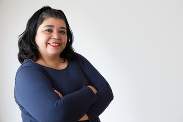 Confident overweight Hispanic woman posing with crossed arms. Successful adult plus size woman. Isolated on white. Success concept - obrazy, fototapety, plakaty