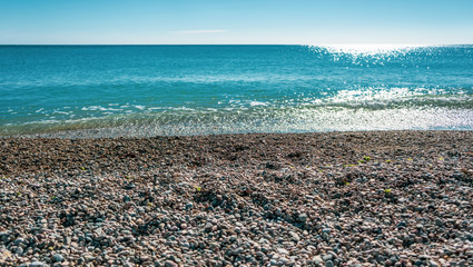 Pebble beach, black sea and blue sky on background