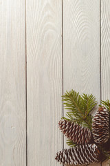 White wooden christmas background with fir branches and cones, top view, copyspace.