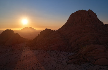 Panoramic, aerial view on a silhouette of a ancient Spitzkoppe mountain against sunset. Rocky desert landscape. Travelling to remote place in Namibia.