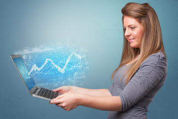 Woman holding laptop projecting financial information, diagrams and charts 

