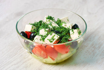 Transparent bowl with salad on a white wooden table