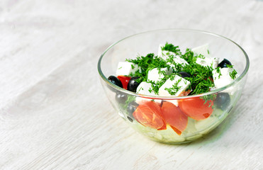Transparent bowl with salad on a white wooden table