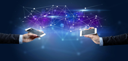 Close up of two hands holding smartphones and sharing business data