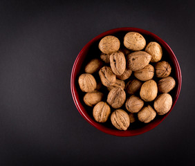 Walnuts in Red Bowl isolated on black background, top view, copy space