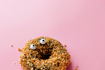 Funny shock face chocolate peanut donut on a pastel pink background, creative minimal Halloween...