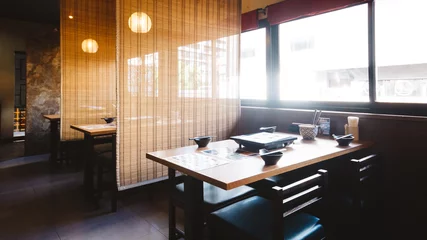 Foto op Plexiglas Restaurant Shabu eettafel set inclusief een houten tafel en vier stoelen met bamboe wand voor privacy.