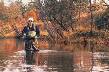 Fisherman makes a cast rod on the autumn creek. Fly fishing