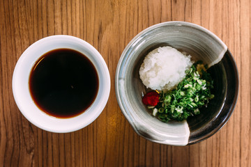 Top view of Shoyu Ponzu (Citrus soy sauce) with minced daikon and scallion.