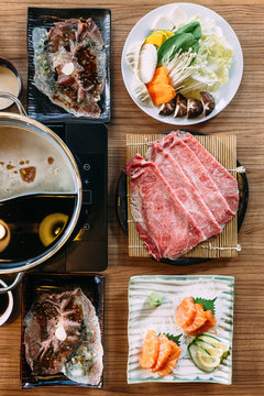 Top view of Shabu set including rare slices Wagyu A5 beef, Shabu shoyu and clear base, salmon, sushi and vegetables. 