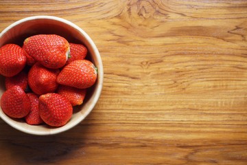 Lovely red fresh ripe strawberry in wood bowl on wooden table, copy space
