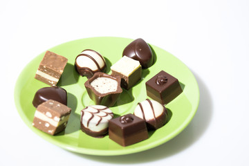 Many chocolates on a green plate isolated in a white background