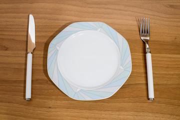 Set porcelain plate and fork and knife on a table