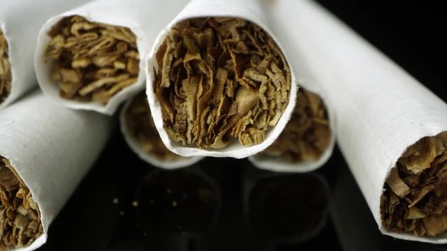Up close shot of cigarettes viewing the tobacco while moving over reflective black table top.