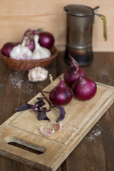 Red onion and garlic with basil on the old wooden background.