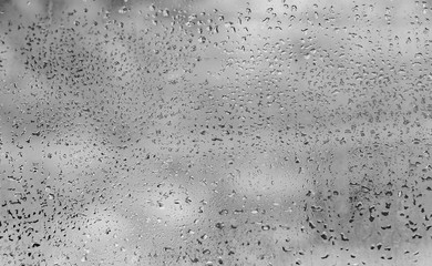 Black and white background of the condensate flowing water on the window glass
