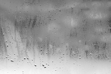 Natural drops of rain on the glass, the view on the street is blurred. Background with water vapor
