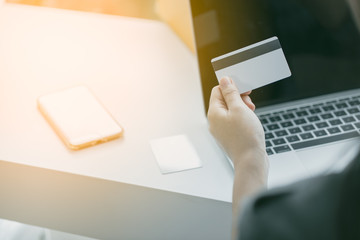 Obraz premium Young woman holding credit card using laptop computer. Online shopping concept.. Online shopping concept.