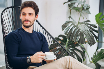 attractive male celebrity holding a cup of coffee and looking aside. close up photo. beauty.