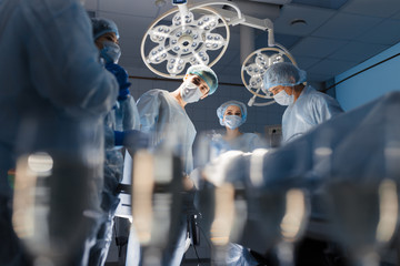 Blurred figures of surgeons in medical uniforms performing surgery in operation theatre, copyspace