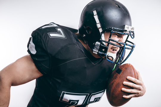 Quarterback attacks with a ball in a professional football game. Profile view.