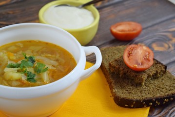 Delicious homemade soup from fresh cabbage on a wooden background.
