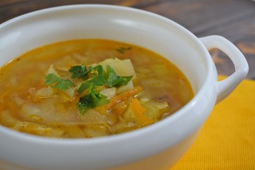 Delicious homemade soup from fresh cabbage on a wooden background.