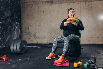 disadvantages of eating fast food. full length photo. hungry sportswoman. girl destroys her...