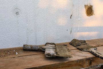 Two spatulas with mortar on old wooden board