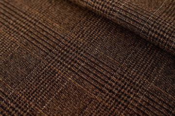 Texture of checkered fashionable fabric. Checkered fabric in brown, gold and black colors creates a textural background. Fabric for sewing clothes.