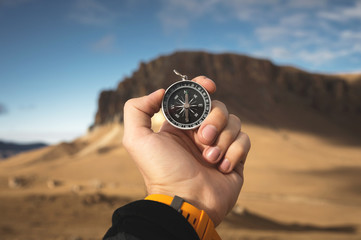 A male Hiker is looking for a direction with a magnetic compass in the mountains in the fall. Point...
