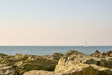 Scenic view of the sea from the rocks with a sailboat on the horizon, Genoa, Italy