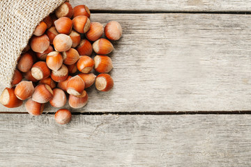 Hazelnuts in a cover, poured out from a bag from burlap on a gray wooden table