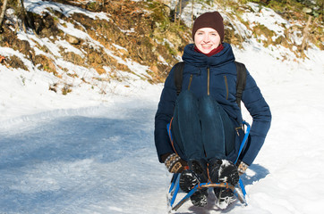 Fototapeta na wymiar Laughing girl rides a small sled. Winter sunny day