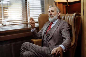 Portrait of trendy fashionable old man in formal suit and glasses, wearing expensive wristwatch,...