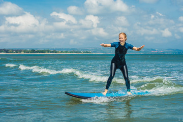 Joyful young woman beginner surfer with blue surf has fun on small sea waves. Active family...