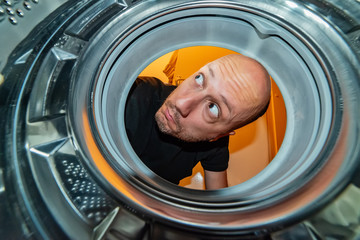 Portrait of man view from washing machine inside. What is that thing inside the washing machine?