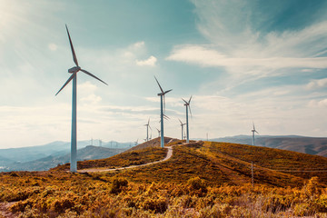Wind turbines on beautiful sunny summer autumn mountain landsape. Curvy road through mountain Eolic park. Green ecological power energy generation. Wind farm eco field - Powered by Adobe