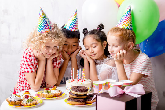 pensive shy kids around the birthday cake. closeup photo.