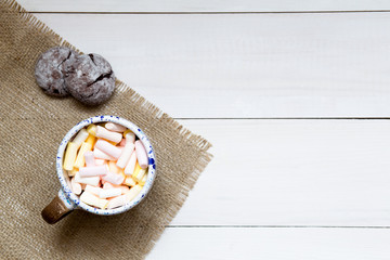 Cup of colorful marshmallows on the wooden table, top view