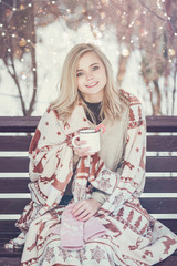 Pensive relax and happy girl with a warming drink sitting in the winter forest